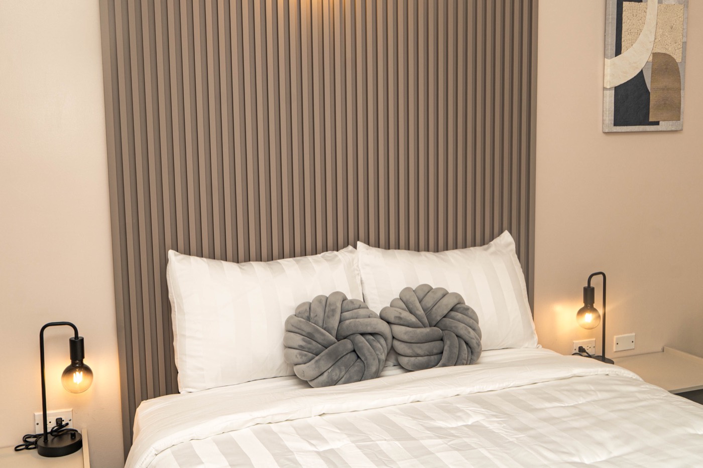 Queen bed with a fluted wood headboard and bedside lamps