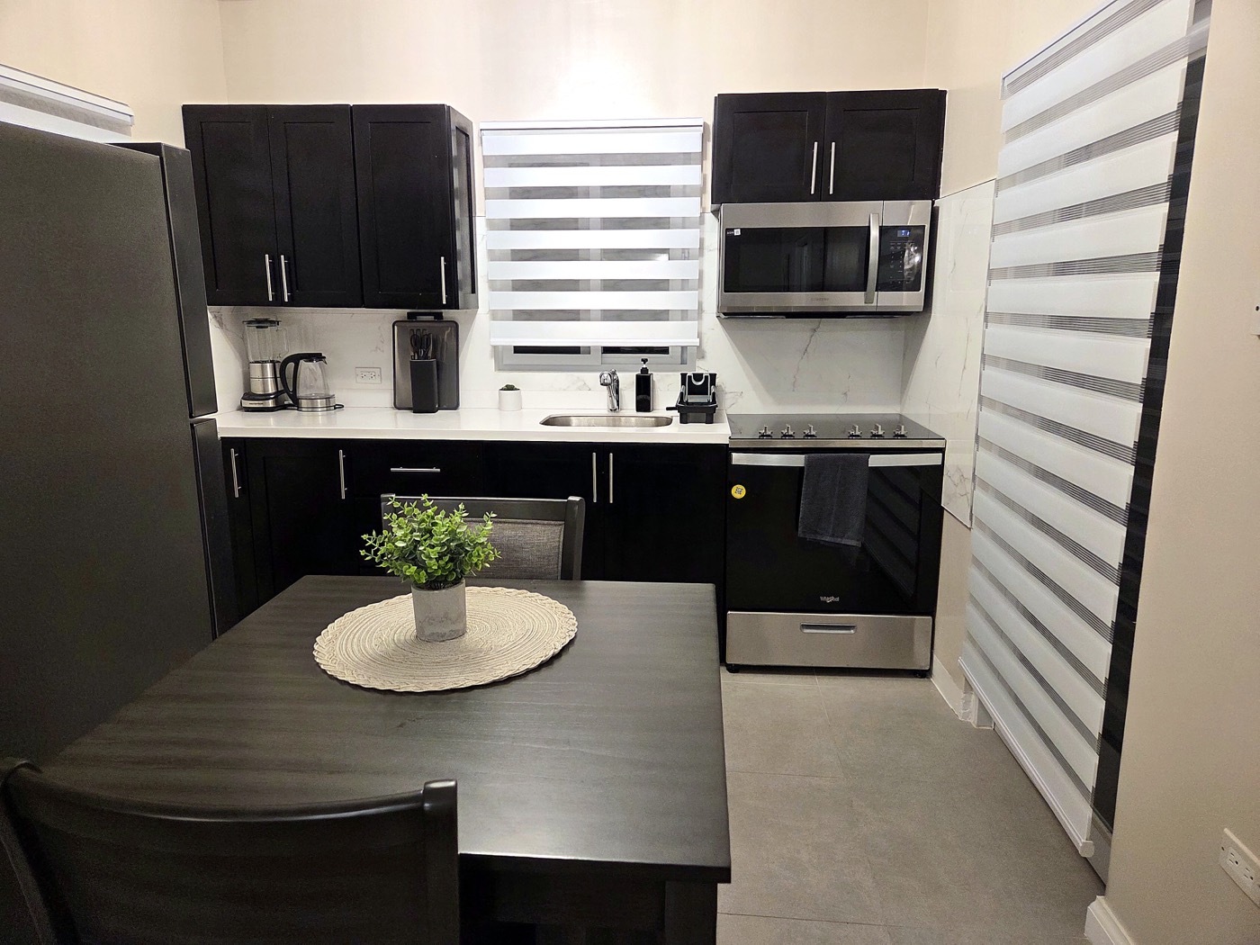 Kitchen with dark cabinetry, electric range, microwave and dining table