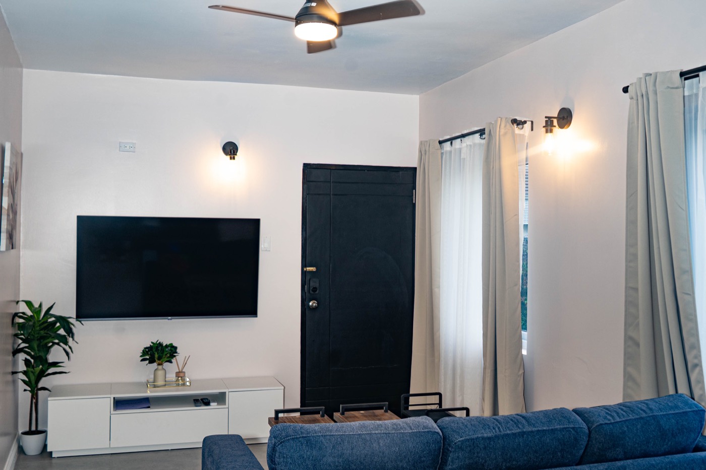 Wall-mounted TV above a media console, ceiling fan overhead